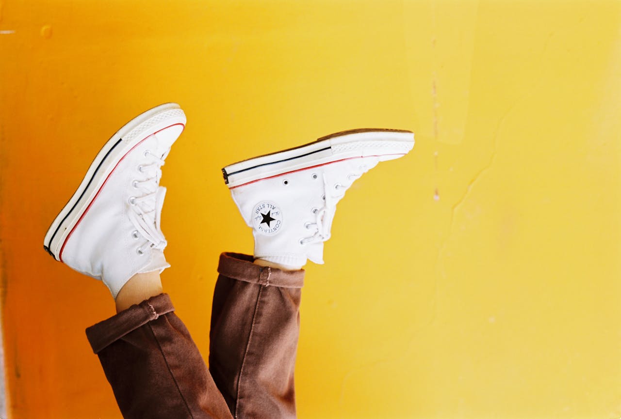 creative Upside down image of white sneakers against a vibrant yellow background, showcasing trendy footwear style.